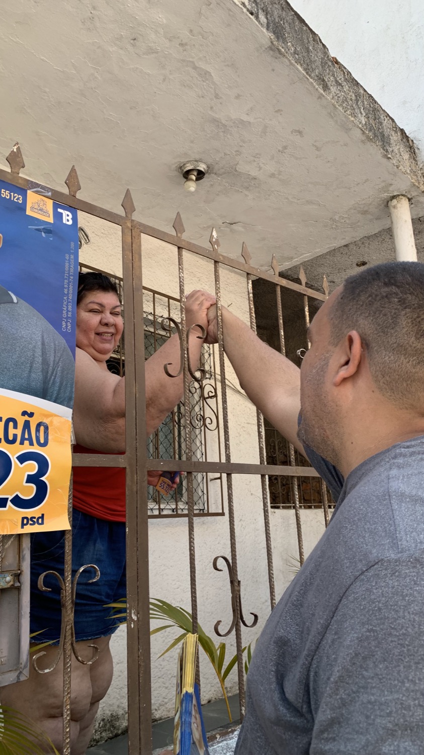 Tiago Bonecão cumprimentando uma moradora na porta de casa